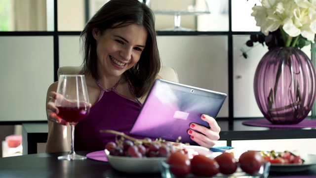 Happy  woman watching movie on tablet  by the table at home