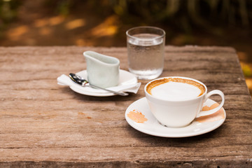 Cup of hot cappuccino coffee on wooden table.