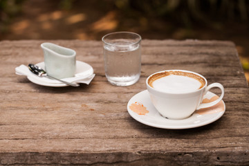 Cup of hot cappuccino coffee on wooden table.