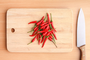 A pile of red chilli peppers on wooden chopping board