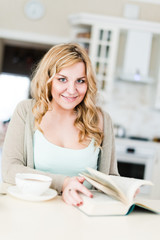 Beautiful woman reads an interesting book and drinks coffee