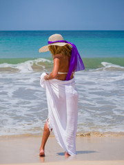 Fototapeta na wymiar woman on beach with tropical sarong and hat