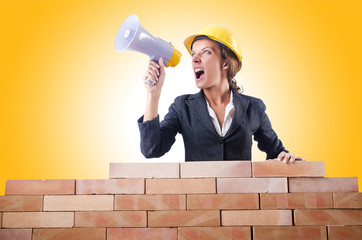 Woman builder with loudspeaker on white