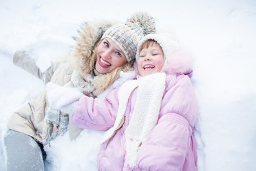 Happy mother and child have fun on snow in winter outdoor