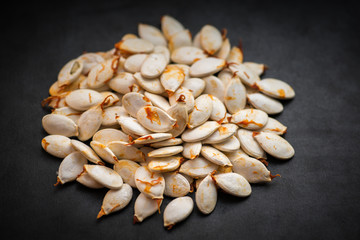 Roasted pumpkin seeds on the dark background. Selective focus.