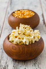 Popcorn and Ripe Corn in Wooden Bowls on White Wooden Table