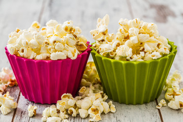 Pile of Popcorn in Colorful Bowls, on White Table Background