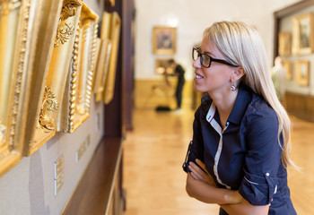Woman looking at old paintings in art gallery