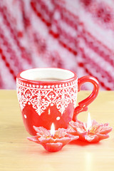 Cup of hot cocao with red poinsettia candle