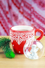 Cup of hot cocao with christmas glass toy and pine
