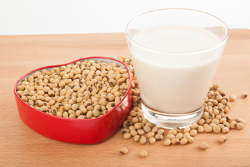 Soy milk in glass with soybeans in heart shape box