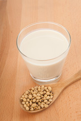 Soy milk in glass with soybeans and wooden spoon