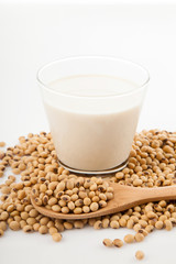 Soy milk in glass with soybeans and wooden spoon