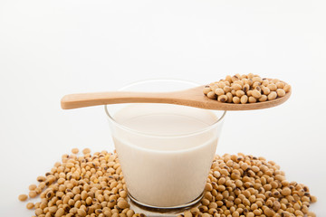 Soy milk in glass with soybeans and wooden spoon