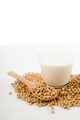 Soy milk in glass with soybeans and wooden spoon