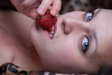 Close up on face with woman biting a strawberry