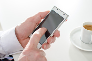 Businessman texting with smartphone and drinking a coffee