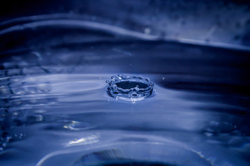 Water drop into a bowl on blue background