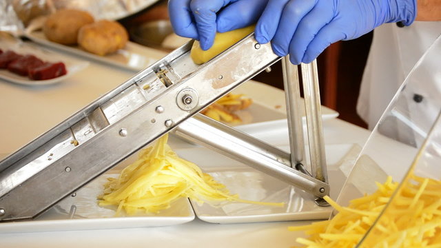 Professional chef hands cutting potatoes with mandolin