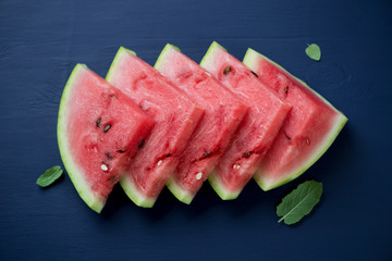 Above view of watermelon slices over dark blue wooden surface