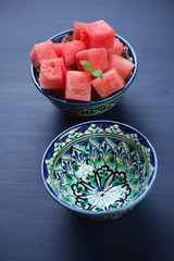 Watermelon cubes in ceramic bowls, dark blue background
