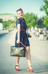 Beautiful woman in fifties style with braces holding retro camer