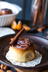Cinnabon cinnamon rolls, almonds and mandarins on a dark plate