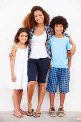 Fototapeta premium Mother And Children Standing Outdoors Against White Wall