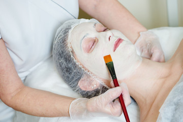 Spa cosmetologist applying facial mask