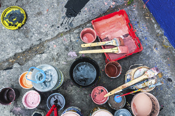 Vertical view of a group of cans with paint of different colors and brushes