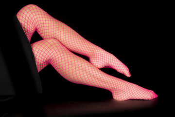 Woman legs in pink fishnet one over other