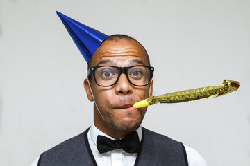 Young geek celebrating with party blower and hat - 74400085