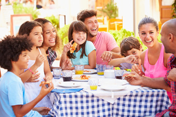 Two Families Eating Meal At Outdoor Restaurant Together