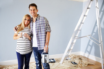 Portrait Of Couple Decorating Nursery For New Baby