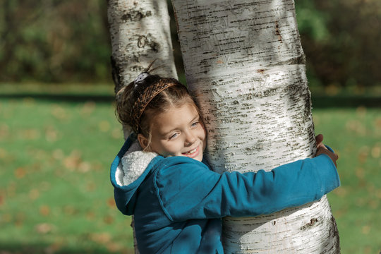 happy beautiful little girl hugging birch tree i autumn park