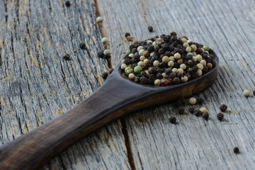 black ,white, green, brown peppercorns on rustic wooden table