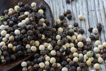 black ,white, green, brown peppercorns on rustic wooden table