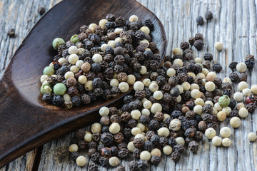 black ,white, green, brown peppercorns on rustic wooden table
