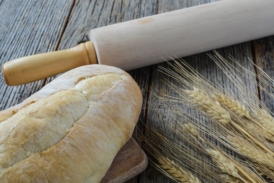Fresh Bread with a Rolling Pin and Wheat on a Rustic Wood Table