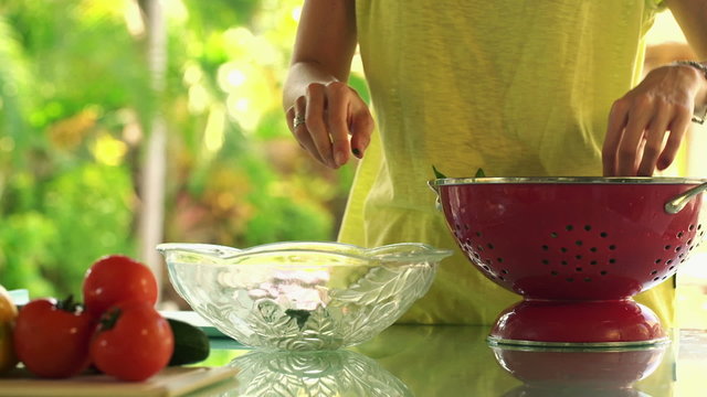 Woman hands picking spinach leaves into glass bowl