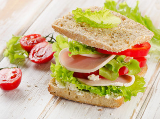 Sandwich with turkey and fresh vegetables on  a wooden table