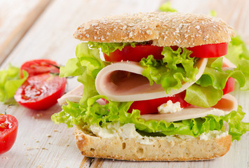 Sandwich with  fresh tomatoes on  a wooden table