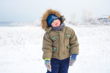 Cheerful little boy standing on a white background winter