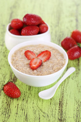 Tasty oatmeal with strawberry on table close-up