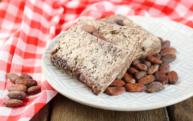 Fototapeta premium Sunflower halva with cocoa on plate, on wooden background