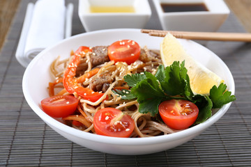 Chinese noodles with vegetables and roasted meat in bowl