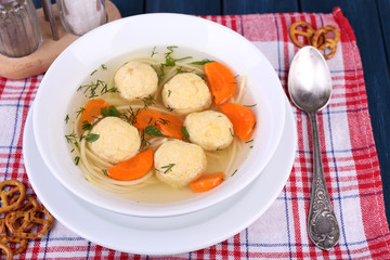 Soup with meatballs and noodles in bowl on wooden background