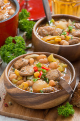 delicious vegetable stew with sausages in wooden bowl, vertical