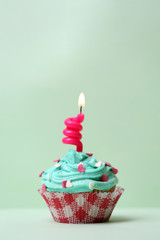 Delicious birthday cupcake on table on light background