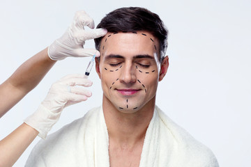 Obraz premium Man with closed eyes at plastic surgery with syringe in his face